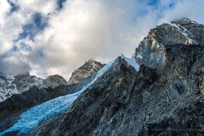 Pumori Glaciers and Golden Light in the Nepal Himalayas Golden sunlight breaks through drifting clouds to illuminate the towering rock faces and rugged ridges near Mount Pumori in Nepal's Everest region. A striking...