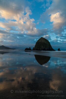Haystack Rock Reflected at Blue Hour, Cannon Beach Haystack Rock rises above the wet shoreline at Cannon Beach, Oregon, beneath a dramatic blue-hour sky. Calm reflections across the sand mirror the sea stack and...