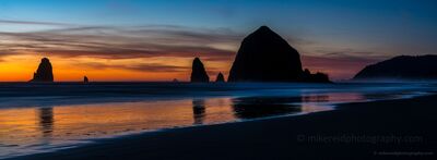 Haystack Rock at Sunset, Cannon Beach Haystack Rock and neighboring sea stacks rise in silhouette from the Pacific Ocean at sunset along Cannon Beach, Oregon. Warm orange light fades into deep blue...