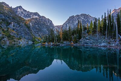 Fall Colors at Dawn on Lake Colchuck Golden autumn larches catch the first light of dawn above Lake Colchuck in Washington’s Alpine Lakes Wilderness. The calm turquoise water reflects the rugged...