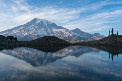Mount Rainier and Sweeping Cloud Reflections in an Alpine Tarn The glacier-covered summit of Mount Rainier reflects in the still waters of a secluded alpine tarn near the Reflection Lakes area of Mount Rainier National...