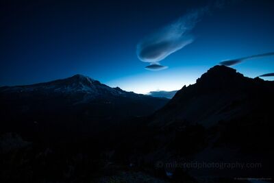 Pre-Dawn Lenticular Cloud Over Mount Rainier from Pinnacle Saddle Moments before sunrise, a rotating lenticular cloud drifts above Mount Rainier, glowing in the deep blue tones of twilight. Captured from Pinnacle Saddle in...