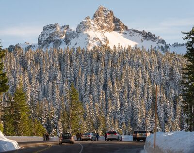 Snowy Road to Paradise – Winter View of the Tatoosh Range, Mount Rainier National Park Evening light warms the snow-covered evergreens and rugged peaks of the Tatoosh Range, seen from the winding road to Paradise in Mount Rainier National Park....