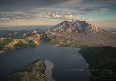 Mount St. Helens and Spirit Lake Aerial Panorama in Evening Light A sweeping aerial view of Mount St. Helens and Spirit Lake in Washington's Cascade Mountains, illuminated by warm evening sunlight. The volcano's open northern...
