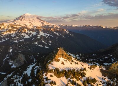Northwest Aerial Photography Chinook Pass Morning Golden morning light washes over Chinook Pass and Mount Rainier, illuminating the rugged ridges and snow-draped slopes of Washington’s Cascade Mountains. The...