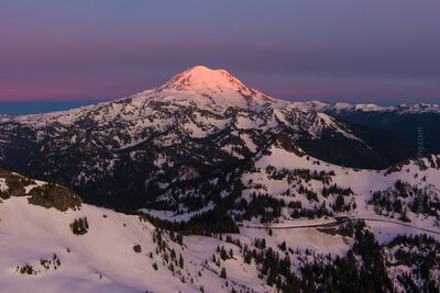 Northwest Aerial Photography Mount Rainier Sunrise The first light of dawn paints Mount Rainier in soft pink and lavender hues, illuminating the snow-covered slopes of Washington’s most iconic peak. Captured in...