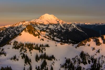 Mount Rainier and Yakima Peak at Sunrise — Pacific Northwest Aerial The first light of sunrise illuminates Mount Rainier and Yakima Peak in a golden alpine glow, revealing the snow-covered ridges and dramatic slopes of...
