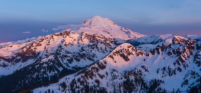 Over Mount Rainier Cowlitz Sunrise Light Aerial Photography An aerial view captures Mount Rainier and the Cowlitz Range bathed in the first light of sunrise. The snow-covered peaks glow in hues of rose and violet beneath...