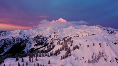 Northwest Aerial Photography Mount Baker Sunrise Over Artists Point A breathtaking aerial view of Mount Baker at sunrise, captured from above Huntoon Point with a DJI Mavic 3 Pro drone. The soft pink alpenglow illuminates the...