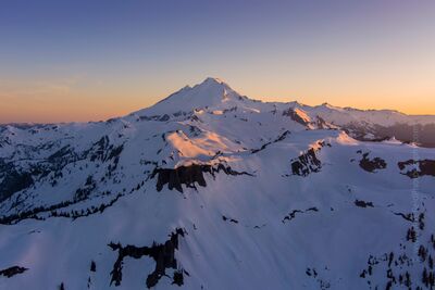 Mount Baker Sunset Light — Aerial View over Table Mountain An aerial view of Mount Baker glowing in the soft golden light of sunset above the snow-covered ridges of Table Mountain. The evening sun casts warm hues across...
