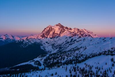 Northwest Aerial Photography Mount Shuksan Sunset A magnificent aerial photograph of Mount Shuksan glowing under the warm hues of sunset in Washington’s North Cascades. The alpenglow paints the snow-covered...