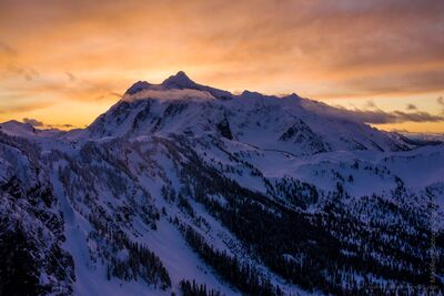 Northwest Aerial Photography Shuksan Sunrise Light A serene aerial view of Mount Shuksan at dawn, bathed in the soft pastel glow of early morning light. The golden and violet hues of sunrise sweep across the...