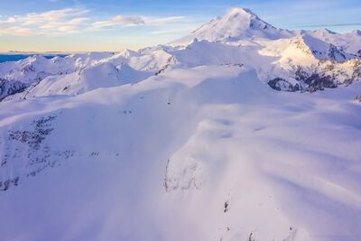 Northwest Aerial Photography Table Mountain Snowscape and Baker An expansive aerial view over the snow-covered summit of Table Mountain with Mount Baker rising majestically in the distance. Captured in soft morning light,...