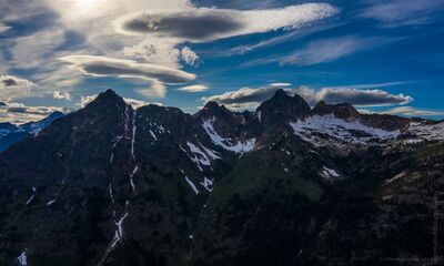 Northwest Aerial Photography North Cascades Lenticulars.jpg Dramatic lenticular clouds form above rugged peaks in Washington’s North Cascades, creating layered shapes across a deep blue sky. Seen from the air, the dark...