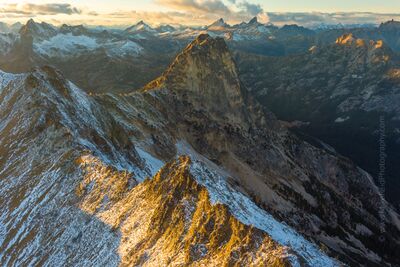 Over the Northwest North Cascades Peaks An aerial perspective from above Kangaroo Pass captures the North Cascades bathed in warm sunset light. Snow-dusted ridges and golden alpine larches glow...