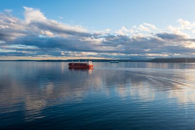 Shipping Vessel on the Salish Sea, Puget Sound Evening Light A red cargo ship glides gracefully across the calm waters of Puget Sound, part of the greater Salish Sea, beneath a dramatic Pacific Northwest sky. The late...
