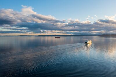 Aerial View of Edmonds to Kingston Ferry Crossing on Puget Sound An aerial perspective captures the Edmonds to Kingston ferry gliding across the calm waters of Puget Sound under soft evening light. The wake of the boat...
