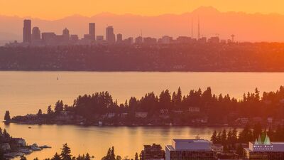 Seattle Skyline Beyond Medina at Sunset Warm sunset light stretches across Lake Washington from Bellevue, with Medina forming the wooded shoreline in the middle distance and the Seattle skyline rising...