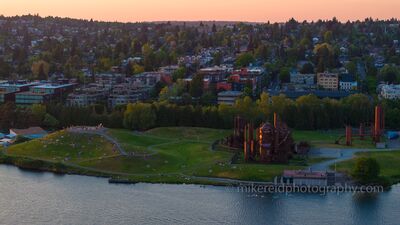 Aerial Seattle Gasworks Park Sunset Golden evening light washes over Seattle’s iconic Gas Works Park as locals gather on the grassy hill to watch the sunset. The warm glow highlights the park’s...