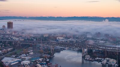 Fog Rolling Over Seattle’s University District Low morning fog rolls across Seattle’s University District while the I-5 Ship Canal Bridge spans the water in the foreground. Buildings emerge through the mist...
