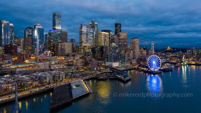 Over Seattle Blue Hour Waterfront Skyline A stunning aerial view of downtown Seattle during the blue hour, where city lights shimmer across the waterfront and the Seattle Great Wheel glows brilliantly...