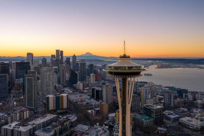 Over Seattle Space Needle Closeup and City at Sunrise Aerial sunrise view of the Seattle skyline with the Space Needle in the foreground and Mount Rainier glowing in the distance. Golden morning light illuminates...