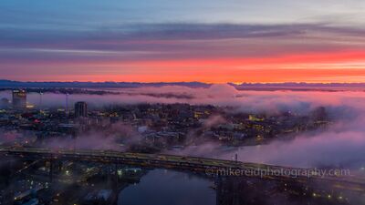 Foggy Sunrise Over Seattle’s University District A dramatic sunrise breaks through low fog over Seattle’s University District, with the I-5 Ship Canal Bridge crossing the foreground and city lights glowing...