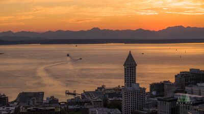 Smith Tower and Elliott Bay at Sunset, Seattle Seattle’s historic Smith Tower rises above downtown as warm sunset light spreads across Elliott Bay and the Olympic Mountains beyond. This aerial view captures...