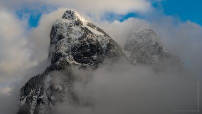 Mount Baring Rising Through Winter Clouds in Washington Snow-covered Mount Baring rises dramatically through swirling clouds in Washington State’s Cascade Range. An aerial view captures the steep rocky summit, winter...