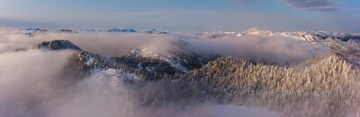 Northwest Aerial Photography Stevens Pass Skyline Lake A breathtaking aerial panorama above Stevens Pass and Skyline Lake as morning clouds drift through the snow-covered Cascades. Peaks rise through the mist in...