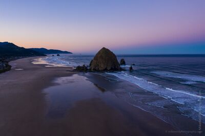 Cannon Beach Sunrise Aerial with Haystack Rock – Oregon Coast Landscape Photography A serene aerial view of Cannon Beach at sunrise, with Haystack Rock rising from the Pacific Ocean as gentle waves and pastel skies meet the quiet shoreline....