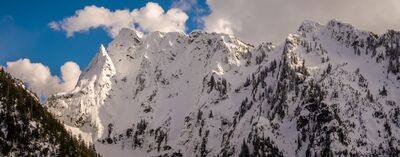 Over the Northwest Mountain Loop Peaks A dramatic winter view along Washington’s Mountain Loop Highway, featuring rugged snow-covered peaks under brilliant blue skies.