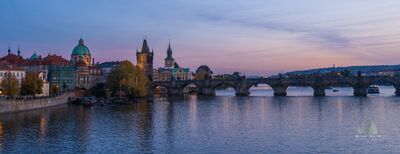 Charles Bridge at Dawn Prague A quiet dawn view of the Charles Bridge spanning the Vltava River in Prague, Czech Republic, with the historic Old Town riverfront glowing softly beneath a...
