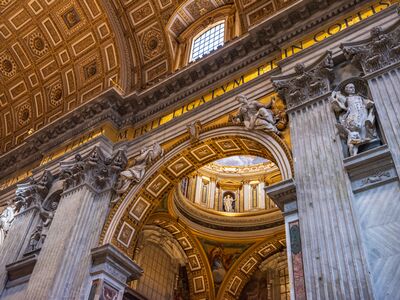 Gilded Arches Inside St. Peter’s Basilica A richly detailed architectural view inside St. Peter’s Basilica in Vatican City, where monumental marble columns, sculpted saints, gilded arches, and coffered...