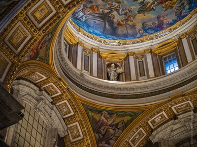 St. Peter’s Basilica Dome Details and Frescoes An upward-looking interior detail of St. Peter’s Basilica in Vatican City, focusing on the sweeping curves of the dome, gilded architectural ornament, painted...