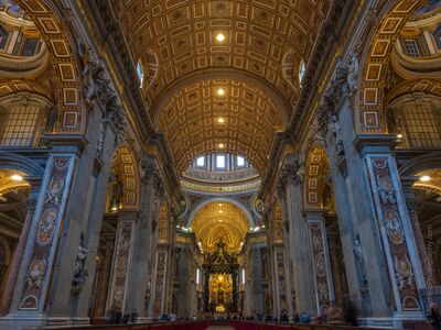 Golden Nave of St. Peter's Basilica A grand view down the nave of St. Peter's Basilica in Vatican City, framed by massive marble piers, richly decorated arches, and a glowing coffered ceiling....