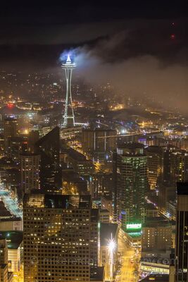 Space Needle in Fog at Night from Columbia Center Seattle’s Space Needle rises through low nighttime fog, its illuminated top glowing above the city lights below. Photographed from the Columbia Center Sky View...
