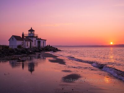West Point Lighthouse Sunset and Tidal Reflections at Discovery Park A vivid pink and coral sunset illuminates West Point Lighthouse at Discovery Park in Seattle, Washington. The receding tide leaves shallow pools and reflective...