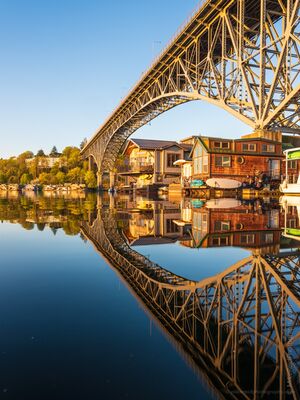 Seattle Lake Union Houseboats and Aurora Bridge Vertical Reflection Vertical view of Seattle’s Aurora Bridge and colorful Lake Union houseboats reflected symmetrically in calm morning water under golden sunlight.