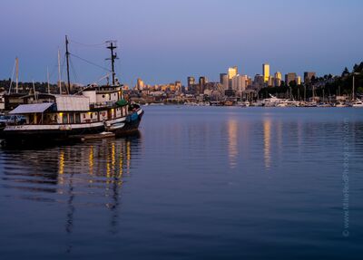 Seattle Skyline and Tug at Sunset Fishing boat and houseboats on Lake Union at sunset with downtown Seattle’s skyline glowing in golden light and reflected in the calm water.