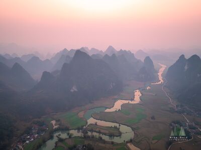 Sunrise Over Phong Nam Valley, Cao Bằng, Vietnam Soft sunrise light spreads across the karst landscape of Phong Nam in Cao Bằng Province, northern Vietnam. A winding river leads through patchwork fields and...